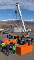 A group of men standing around a truck that is lifting a container photo