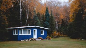 A blue house in the woods with trees and fall foliage photo