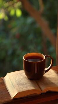 A cup of coffee and an open book on a table photo