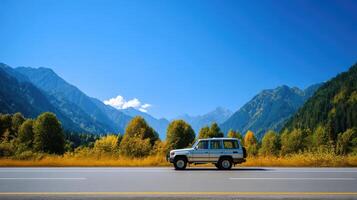 A car is driving down the road in front of mountains photo