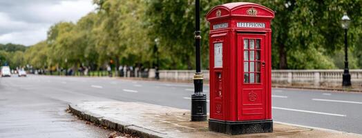 A red telephone box is sitting on the side of the road photo