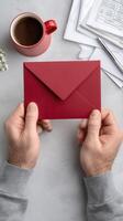 A man holding an envelope with a red envelope on a desk photo