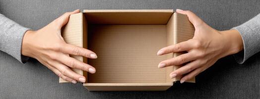 A woman holding a cardboard box over a gray background photo