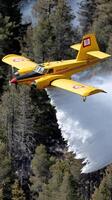 A yellow plane flying over a forest photo