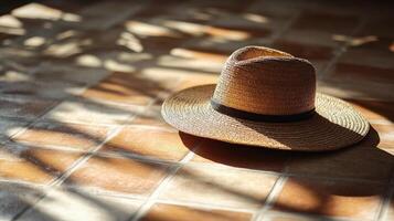 Straw hat resting on sunlit tiled floor photo