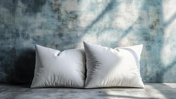 Two white pillows resting on concrete surface against textured wall photo