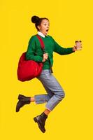 Hurry Up. African american teen is late for college, running with coffee, jumping over yellow background, full length photo