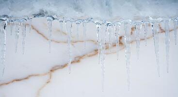 Icicles hanging from the side of a marble wall photo