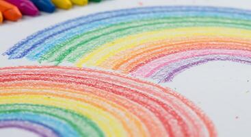 A rainbow is drawn on a piece of paper with crayons photo