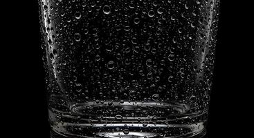 A glass of water with water droplets on the surface photo