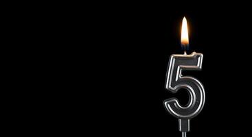 A candle is lit in the shape of the number five photo