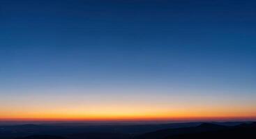 A sunset over the mountains with a blue sky photo