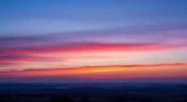 A sunset over the countryside with a blue sky photo