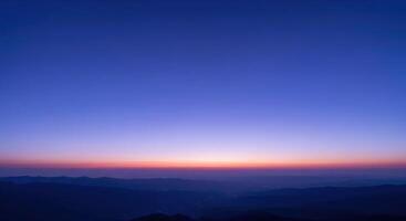A blue sky with a purple sunset over mountains photo