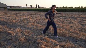 A Young Woman Strolling Through a Dried Field During a Beautiful Sunset Reflection video