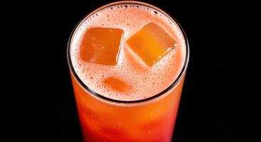 A glass of orange juice with ice cubes photo
