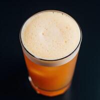 A glass of orange drink sitting on a black surface photo