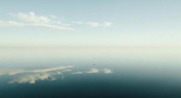 A lone bird is flying in the sky above a calm body of water photo