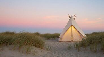 A tent on the beach with a sunset behind it photo