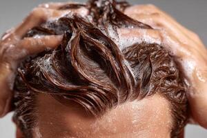 Man washing his hair with shampoo, creating thick foam photo