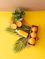 Natural wooden kitchen setup with fresh oranges and plants reflecting eco lifestyle and mindful slow living Flatlay of oranges juice bottle and green plant on wooden background with palm leaves accent photo