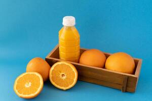 Natural wooden kitchen setup with fresh oranges and plants reflecting eco lifestyle and mindful slow living Wooden crate with oranges and juice bottle on blue background for health food and tropical d photo