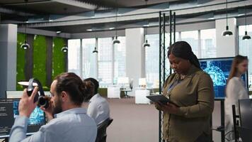 sorridente fêmea engenheiro Próximo para escritório colegas de trabalho em desenvolvimento Programas formulários, integrando ai automação. feliz mulher Próximo para desenvolvedores às trabalhos depuração formulários, Câmera uma video