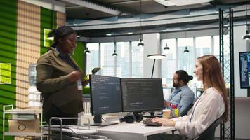 Friendly coworkers helping junior dev code AI algorithms to debug software issues and improve systems, teamwork concept. Welcoming team assisting newcomer in tech startup office, camera A video