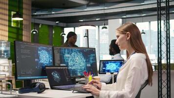 IT expert in high tech startup office uses neural networks to develop artificial intelligence models. Female engineer uses AI to run tasks across devices, monitoring progress on screens, camera A video