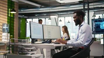 System administrator in tech startup office using PC, troubleshooting hardware and software issues. IT professional at work monitoring and optimizing performance using computer, camera A video