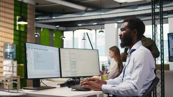 Technician using PC to code, testing applications to minimize bugs, improving system stability. IT specialist in tech startup office optimizing performance through application configuration, camera A video