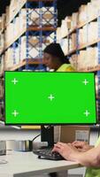 Vertical Asian staff looking at isolated screen shipping route on package tracking software, updating the delivery details on airway bills. Works in warehouse with green screen on computer. Camera A. video