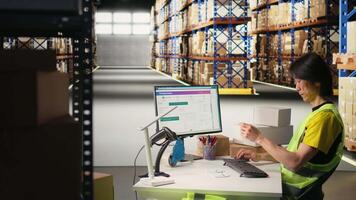 Asian depot worker processing orders and awb tracking numbers to apply on boxes for the delivery process, registering shipment details on package tracking software. Fulfillment center. Camera A. video