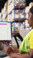 Vertical Young woman scanning barcodes with AI automation systems to handle warehouse operations, managing tracking software service. Shipment details on labels in busy distribution hub. Camera A. video