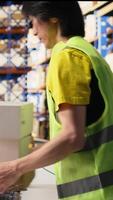 Vertical Staff member scanning barcode tracking info on tags before dispatch, working in warehouse for large scale order fulfillment. Distribution of goods in industrial storehouse facility. Camera A. video