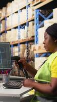 Vertical African american female scanning shipping labels with AI brain neural networks, support for the package tracking software system. Woman handling online shopping orders in warehouse. Camera A. video