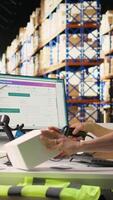 Vertical Asian staff manages awb labeling and scanning barcodes before dispatch, wearing hi vis vest in a warehouse for retail distribution. Ensuring order fulfillment and inventory tracking. Camera A. video