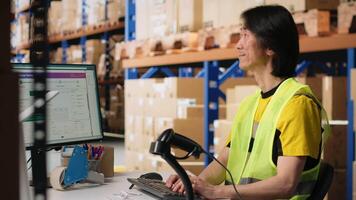 Asian employee registering airway bills in storehouse industrial depot, scanning barcode for shipment details on the package tracking software. Fulfillment center inventory tracking. Camera B. video