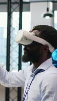 Vertical Admin using virtual reality tech, automating repetitive tasks with AI scripts. Employee wearing VR headset using artificial intelligence to speed up feature implementation, camera A video