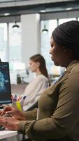 Vertical Jolly female programmer at office desk pleased after developing application using machine learning automation. Joyous employee satisfied after debugging applications using neural networks, camera A video