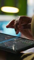 Vertical Close up of engineer using tablet to write code, developing machine learning APIs. IT professional troubleshooting software errors and faults using artificial intelligence, camera A video