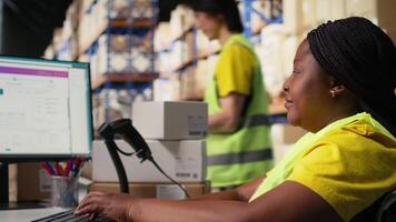 African american worker with disability uses airway bill numbers for tracking info on software, monitoring the order parcel status in a distribution hub. Managing shipment operations. Camera A. video