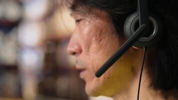 Close up of man in hi vis vest answers a customer service call in a warehouse logistics center, assisting with tracking shipments, fixing a wrong address issue and updating status. Camera B. video