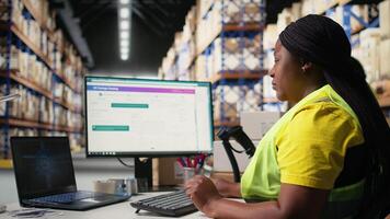 svart kvinna bearbetning order Nästa till hjärna för spårning programvara, använder sig av dator till Registrera spårning tal streckkoder. artificiell intelligens stödjande försändelser. kamera a. video