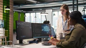 Manager teaching young technician how to develop software and optimize code using AI. Team leader guiding intern in office on how to use artificial intelligence to resolve bottlenecks, camera A video