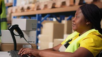 African american worker with disability uses airway bill numbers for tracking info on software, monitoring the order parcel status in a distribution hub. Managing shipment operations. Camera B. video