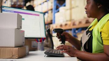 Female worker managing barcodes and shipment details scanning tasks for online shopping orders, goods with shipping labels awb numbers on boxes. Distribution hub staff in hi vis vest. Camera A. video
