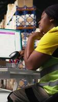 Vertical African american overworked woman struggling to stay awake, dealing with burnout after a long shift of processing orders in industrial warehouse space. Exhausted staff member. Camera A. video