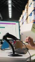 Vertical Industrial staff member in big fulfillment center scanning tags on boxes, registering shipping labels for express delivery logistics with a barcode scanner. Order tracking for e-commerce. Camera A. video