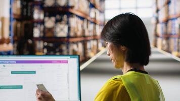 Asian depot worker processing orders and awb tracking numbers to apply on boxes for the delivery process, registering shipment details on package tracking software. Fulfillment center. Camera B. video